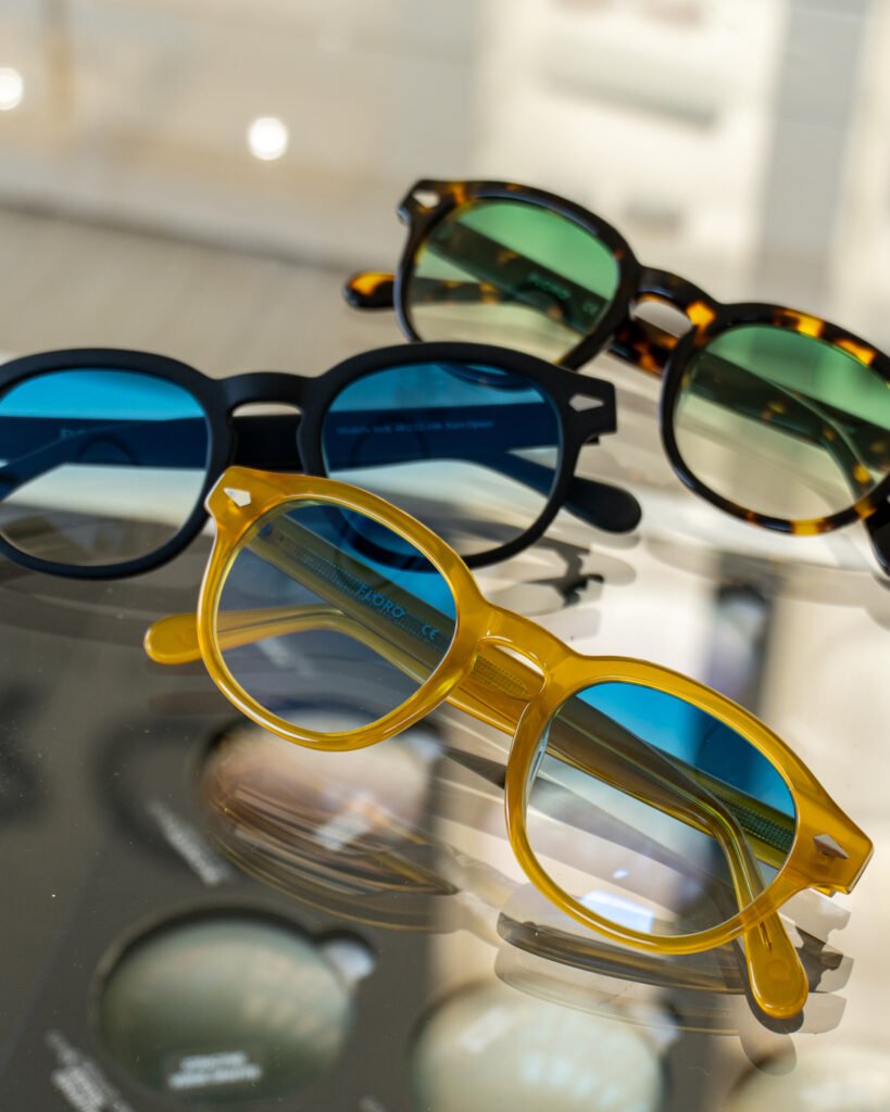 Occhiali da sole Floro in acetato miele, nero opaco e tartaruga con lenti colorate sul banco del negozio